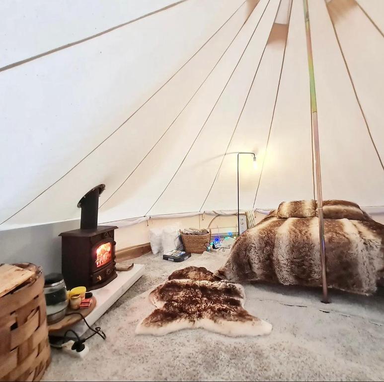 a bedroom with a bed and a fireplace in a tent at Karula Stay - Exclusive Glamping Experience with Private Sauna in Ähijärve