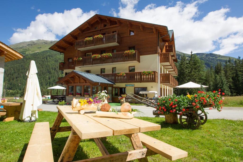 a wooden picnic table in front of a building at Hotel Cevedale in Santa Caterina Valfurva