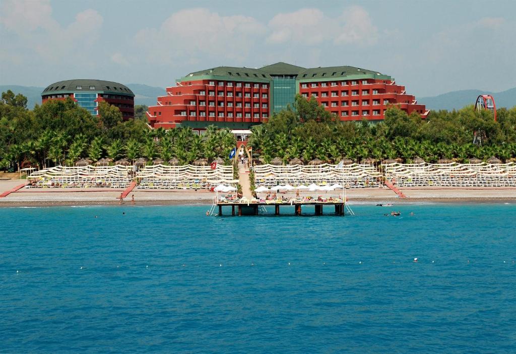 uma praia com cadeiras e um cais na água em Delphin Deluxe Resort em Okurcalar