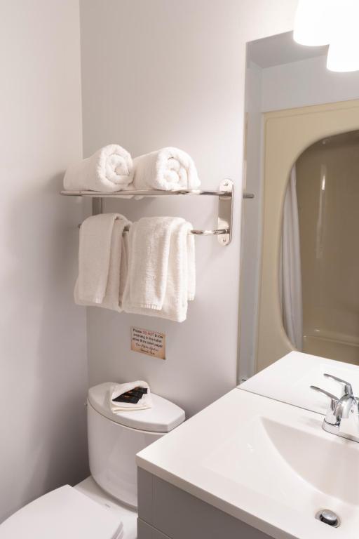 a bathroom with a toilet and a sink and towels at Schott's Lake Conference & Resort in Sundre