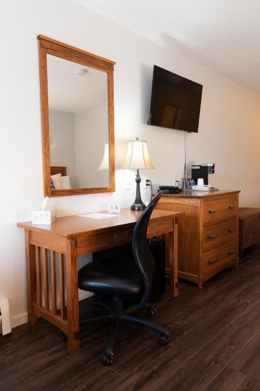a desk with a mirror and a chair in a room at Schott's Lake Conference & Resort in Sundre