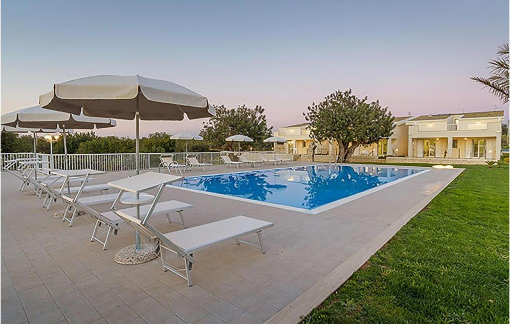 una piscina con sedie e ombrelloni accanto a una casa di Gorgeous Home In Santa Croce Camerina With Swimming Pool a Santa Croce Camerina