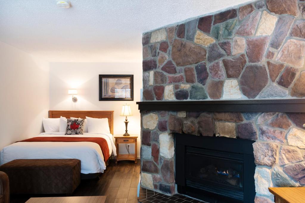 a hotel room with a fireplace and a bed at Schott's Lake Conference & Resort in Sundre