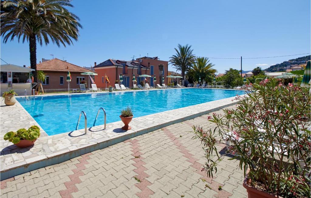 una gran piscina con palmeras y edificios en Casa Borgo 2, en Pietra Ligure