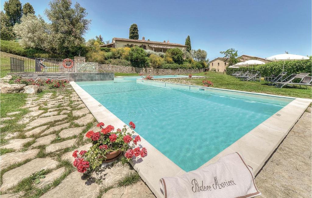 a swimming pool with flowers and a house at La Scuderia-podere Moricci in Montaione