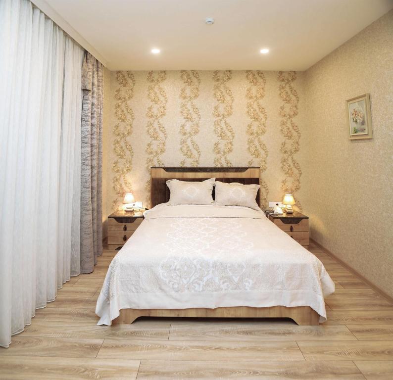 a bedroom with a white bed with two night stands at MidCity Hotel in Baku