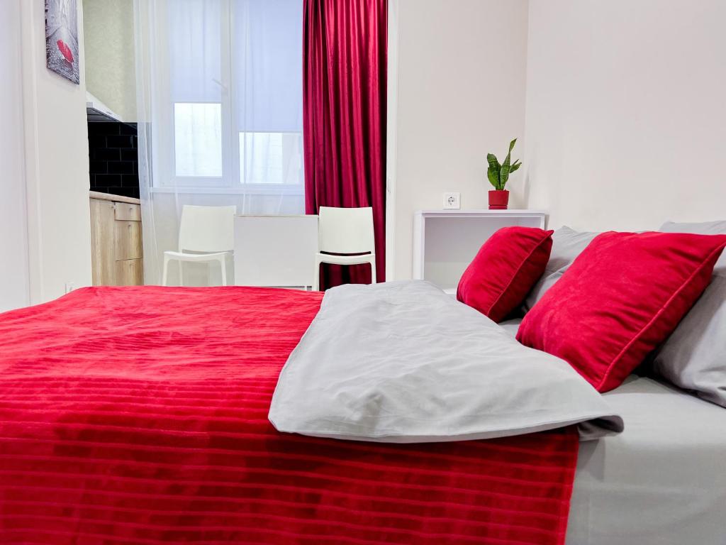 czerwono-białe łóżko z czerwonymi poduszkami w obiekcie Новая студия на Южном вокзале w Charkowie
