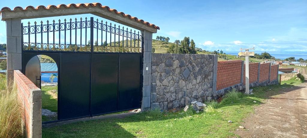 ein großes schwarzes Tor mit einer Steinmauer in der Unterkunft Alberto homestay taypi qamaña establo in Juliaca