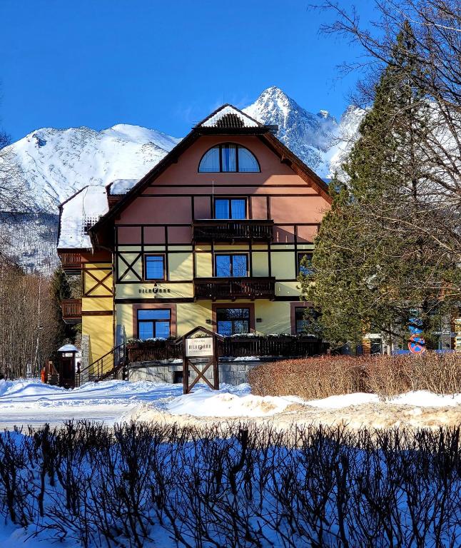 a large building with snow covered mountains in the background at Penzión Vila Park in Tatranská Lomnica