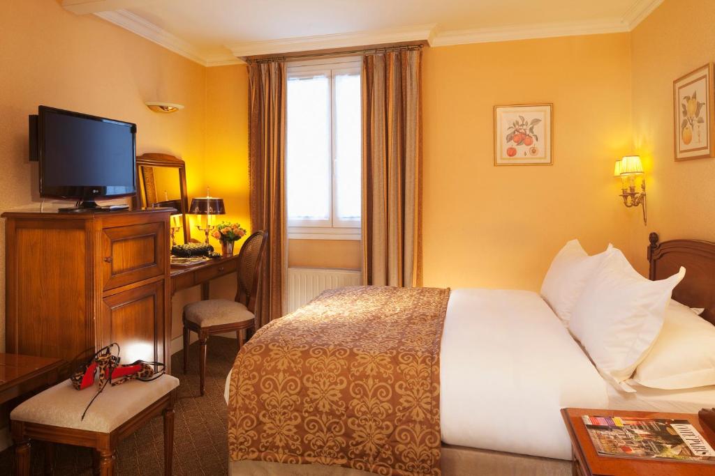 a hotel room with a bed and a desk and a television at Hôtel de Varenne in Paris