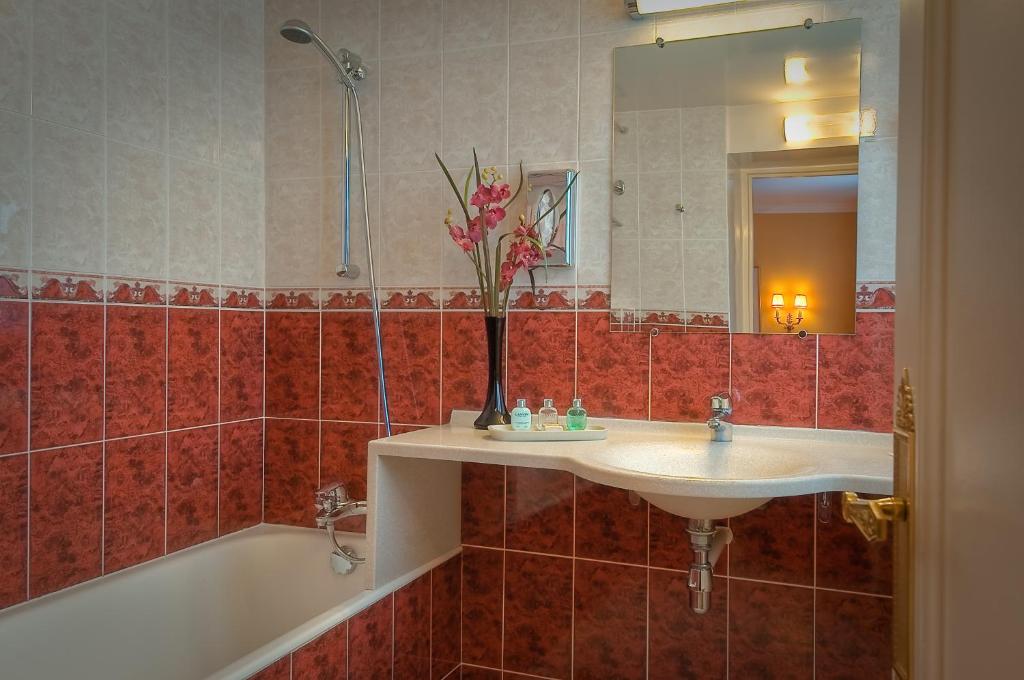 a bathroom with a sink and a bath tub at Hôtel de Varenne in Paris