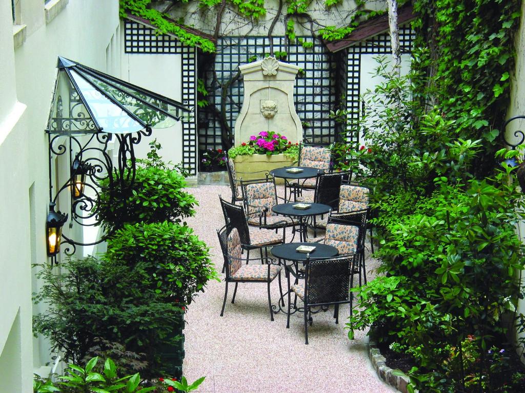 un patio avec des tables et des chaises dans un jardin dans l'établissement Hôtel de Varenne, à Paris