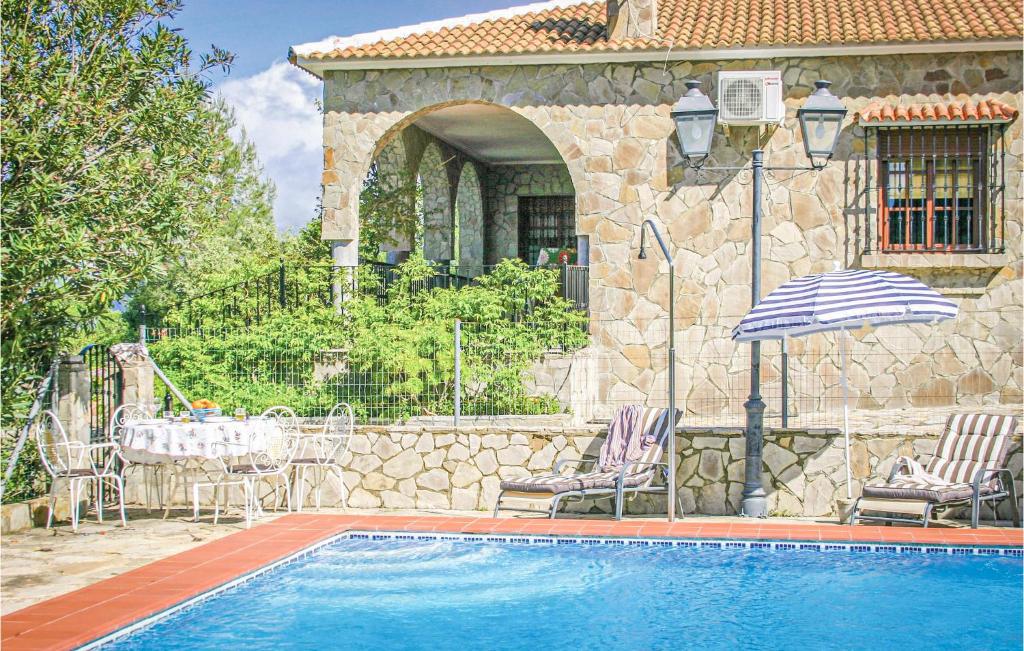 a house with a swimming pool with two chairs and an umbrella at Awesome Home In El Gastor With 3 Bedrooms, Wifi And Outdoor Swimming Pool in El Gastor