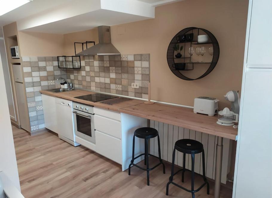 a kitchen with a counter and two bar stools at CHECK-IN CASAS El rinconet in Cerler