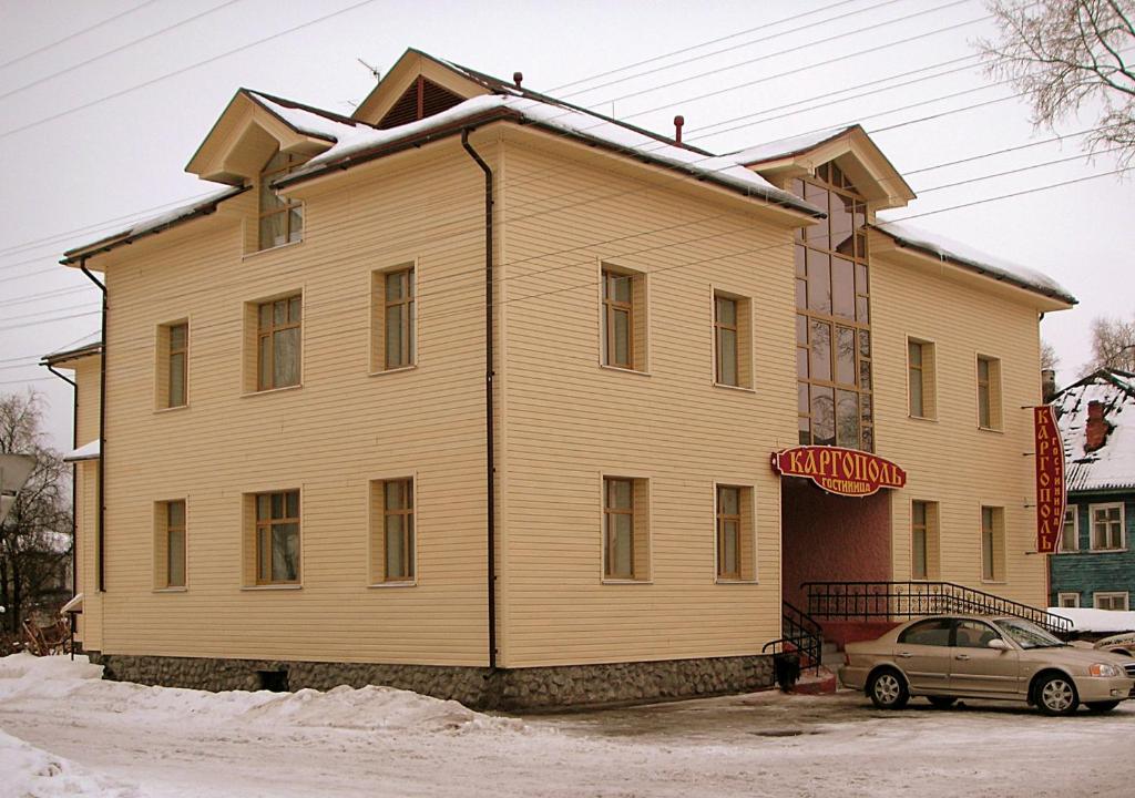 ein großes Holzhaus mit einem Auto davor geparkt in der Unterkunft Kargopol Hotel in Kargopol'