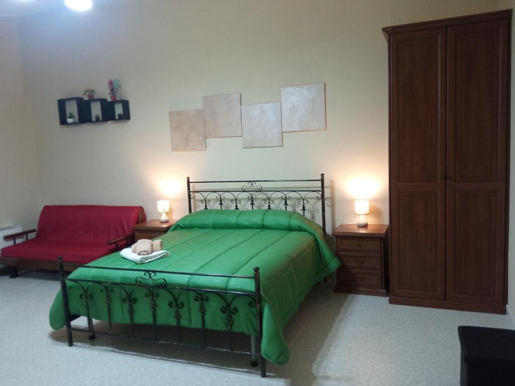 a bedroom with a green bed and a red chair at L'altra casa 1933 in Rionero in Vulture