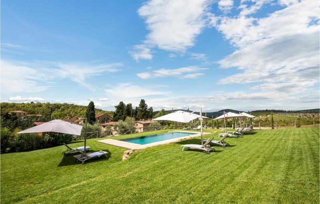 a pool with chairs and umbrellas in a field at Casa Chiara in Gaiole in Chianti