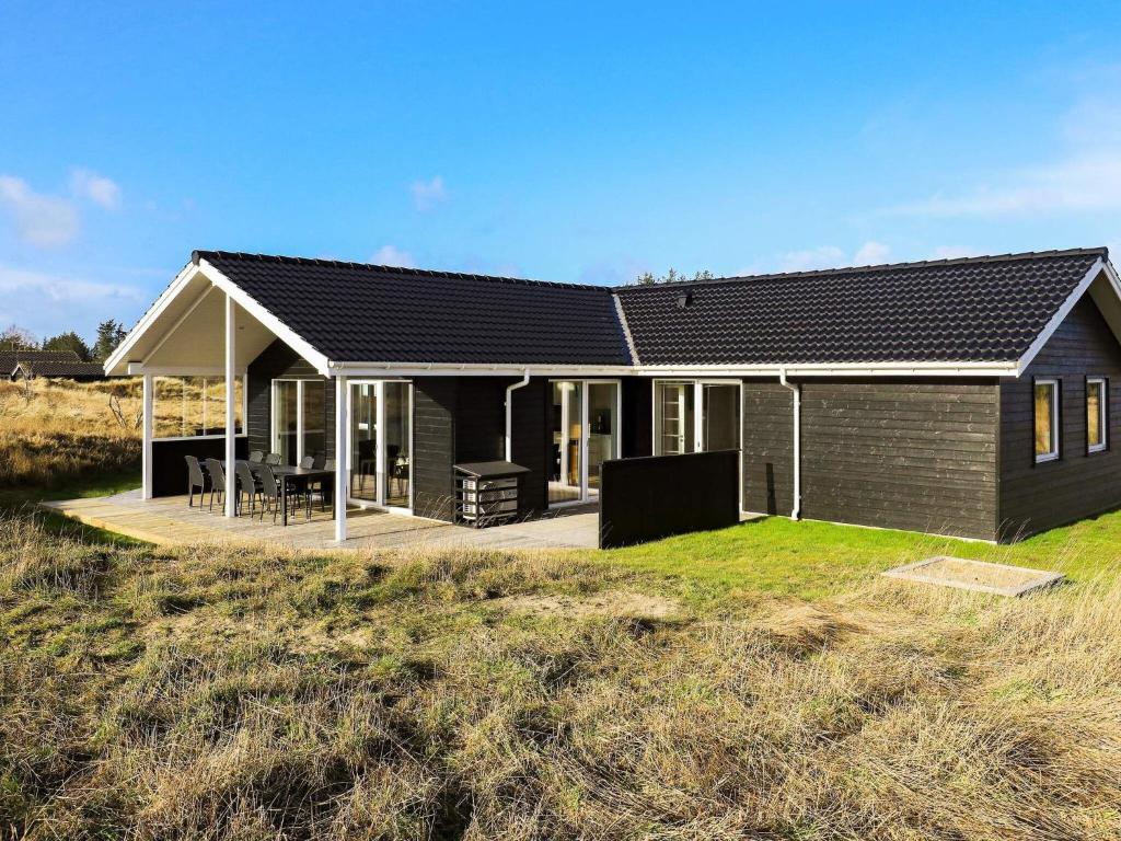 uma casa negra com um alpendre num campo em 8 person holiday home in Hirtshals em Hirtshals