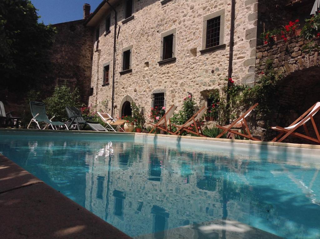 Tavernelle的住宿－Palazzo del Duca，石头建筑前的游泳池