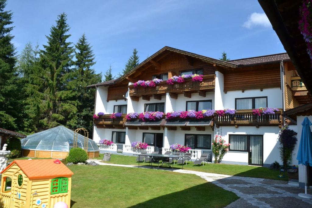 ein großes weißes Gebäude mit Blumen auf den Balkonen in der Unterkunft Hotel Ramsaueralm in Ramsau am Dachstein
