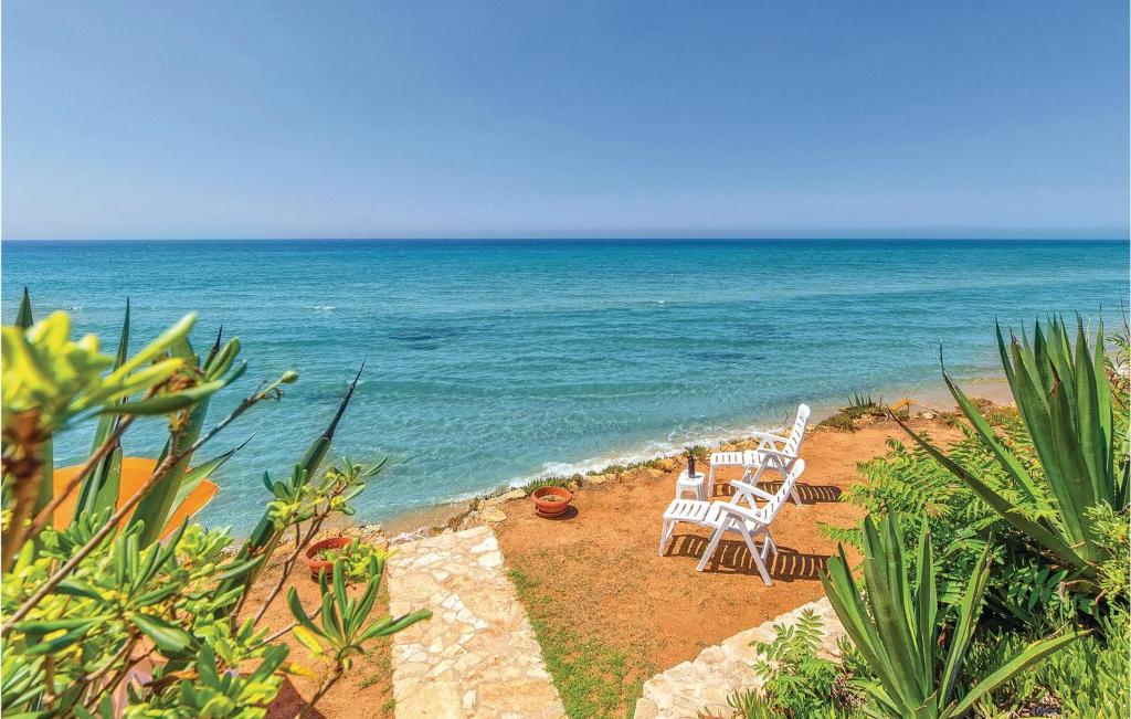 メンフィにあるNice Home In Menfi Ag With 3 Bedrooms And Wifiの海辺のビーチに座る白い椅子2脚