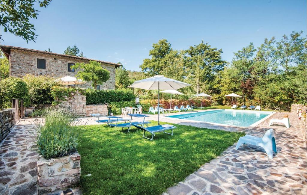 a backyard with a pool with chairs and an umbrella at Camelia in Lucolena in Chianti