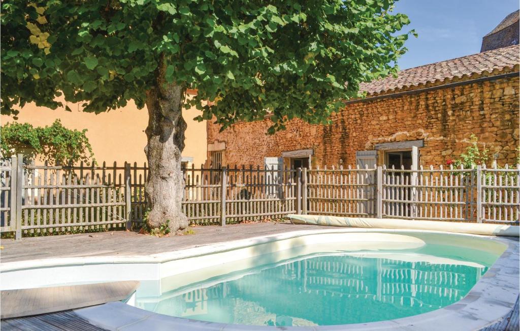 a swimming pool with a tree in front of a fence at Stunning Home In Sainte Alvre With 6 Bedrooms, Sauna And Private Swimming Pool in Saint-Alvère