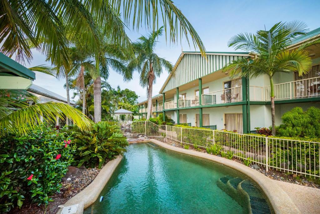 a swimming pool in front of a building with palm trees at Shamrock Gardens Motel in Mackay