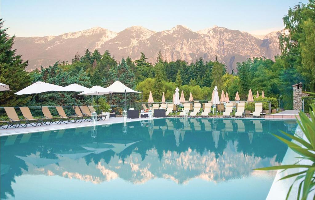 uma piscina com cadeiras e montanhas ao fundo em Residence Le Rose em Tremosine Sul Garda