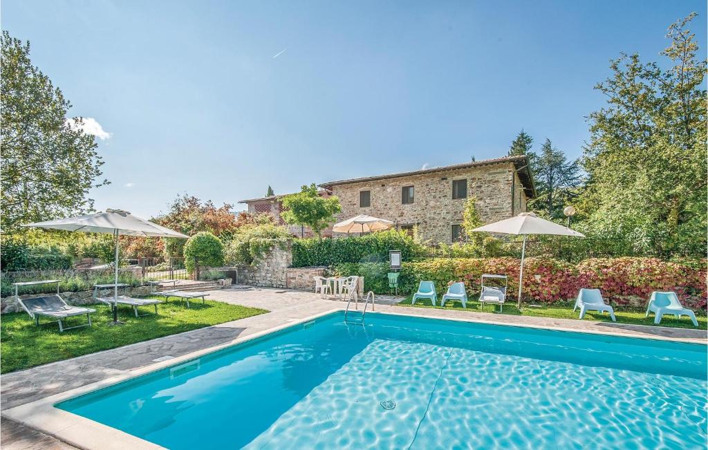 a pool with chairs and umbrellas next to a house at Dahlia in Lucolena in Chianti