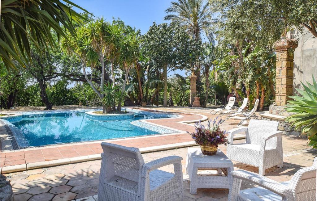 a swimming pool with white chairs and a table and a tablektop at Stunning Home In Saline Ioniche in Saline Joniche