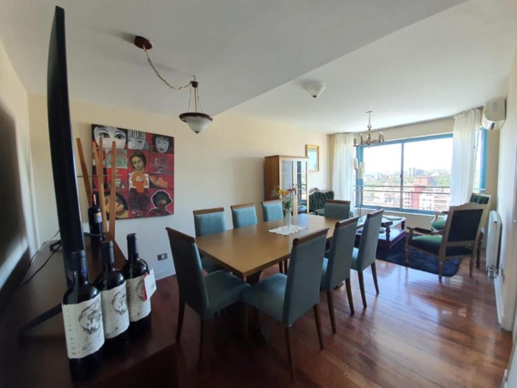 uma sala de jantar com uma mesa com cadeiras e garrafas de vinho em Mendoza Premium Suites - Dpto de Lujo Piso 14 - Vista A La Montaña! em Mendoza
