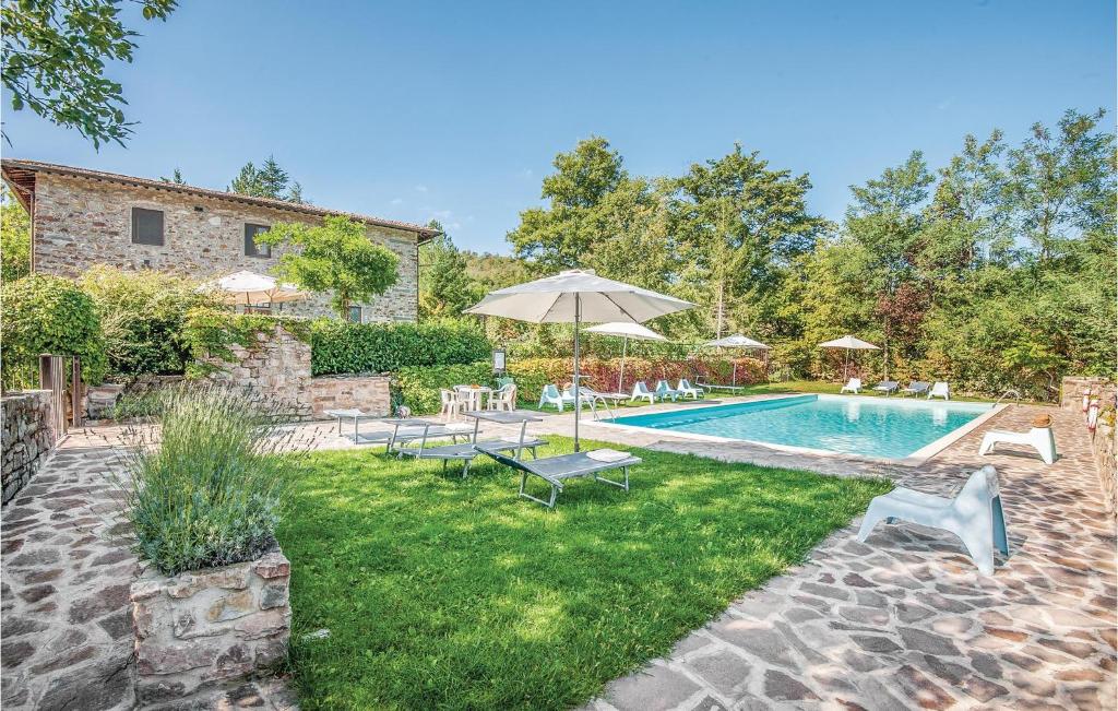 un patio trasero con piscina con sillas y sombrilla en Magnolia, en Lucolena in Chianti