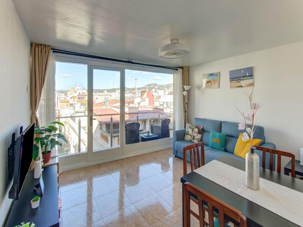 a living room with a table and a couch and a large window at Belvilla by OYO Apartment in Lloret de Mar in Lloret de Mar