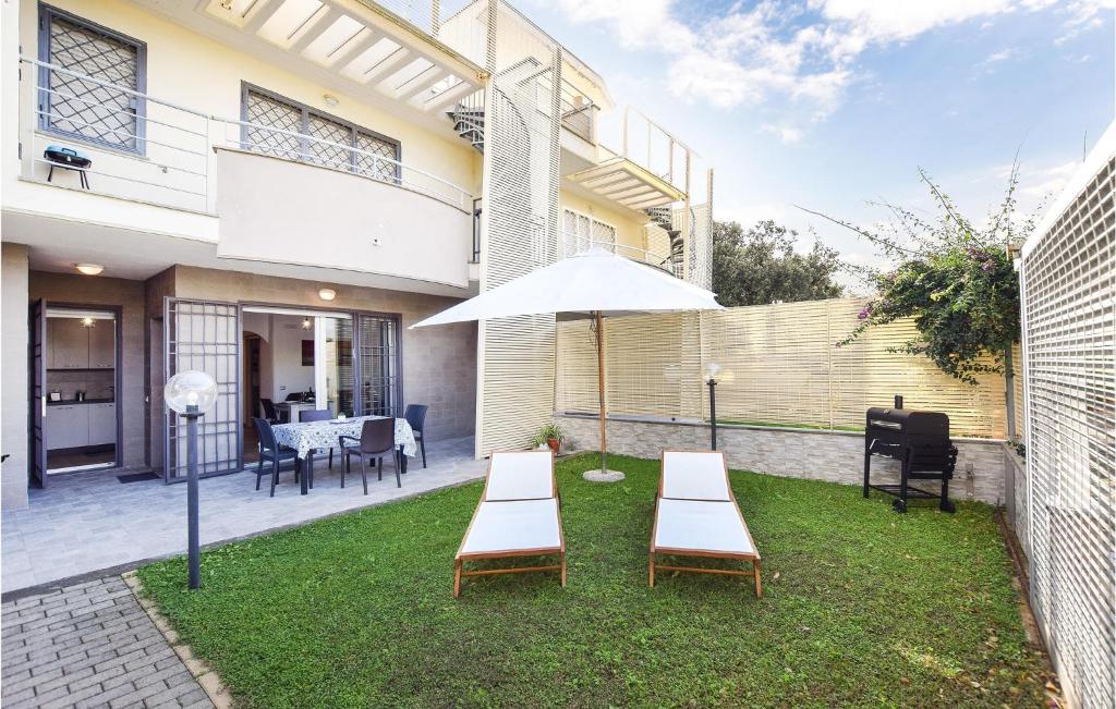 een patio met 2 tafels en een parasol bij Lovely Apartment In Anzio With Kitchen in Anzio