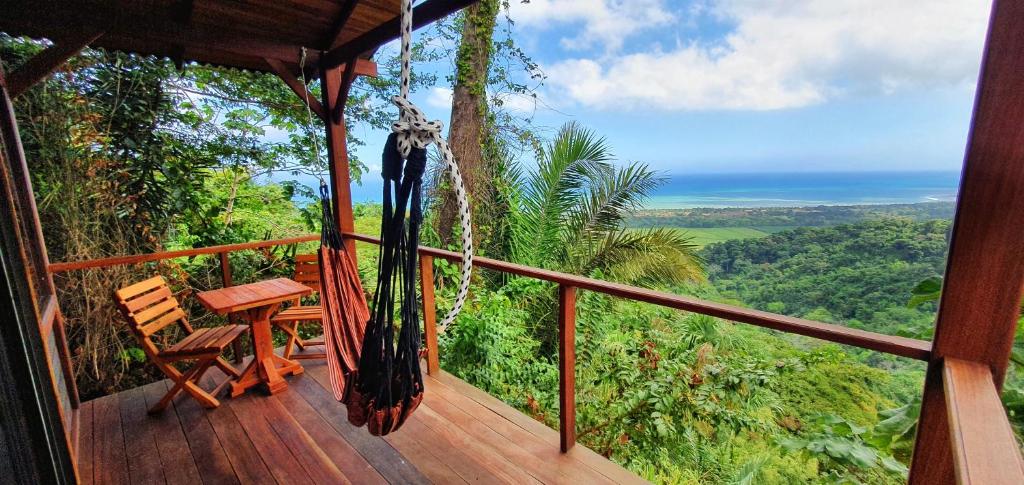 a porch with a hammock and a table and a view of the ocean at Finca Cuipo in Buritaca