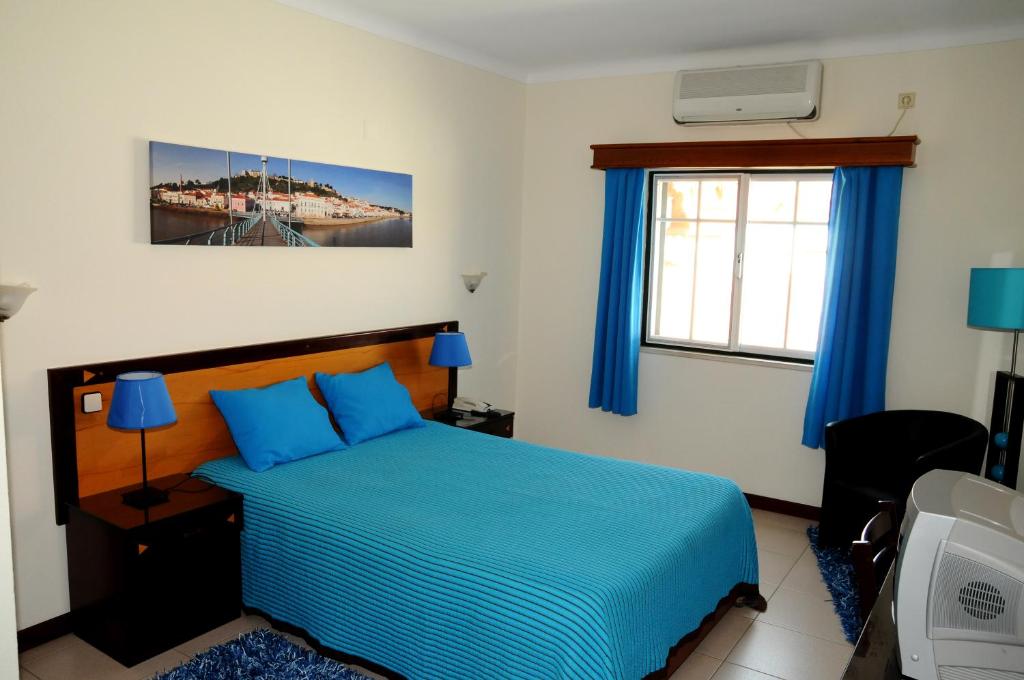 a bedroom with a blue bed and a window at Hotel A Cegonha in Alcácer do Sal