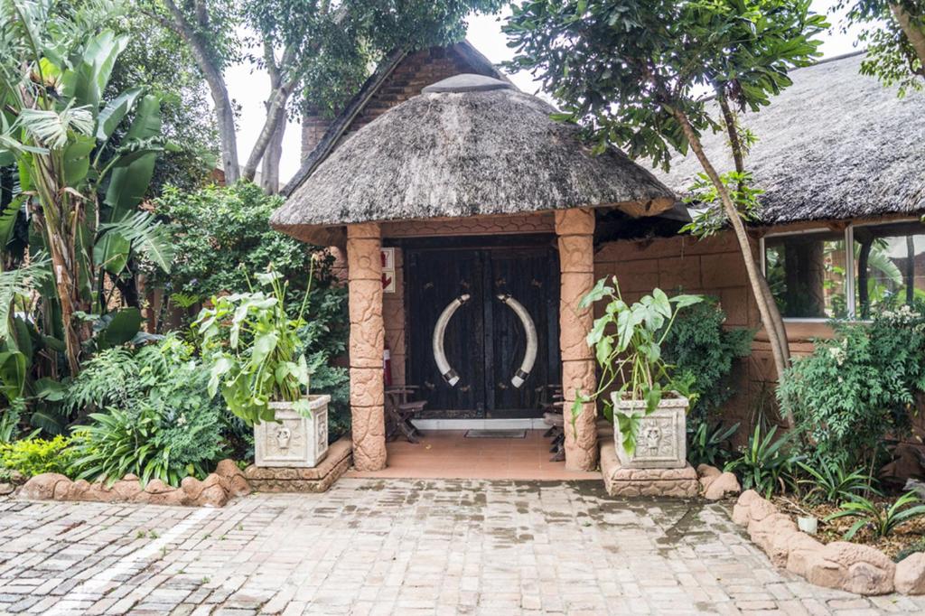 a gazebo with a black door in a garden at Ivory Lodge Bendor in Polokwane