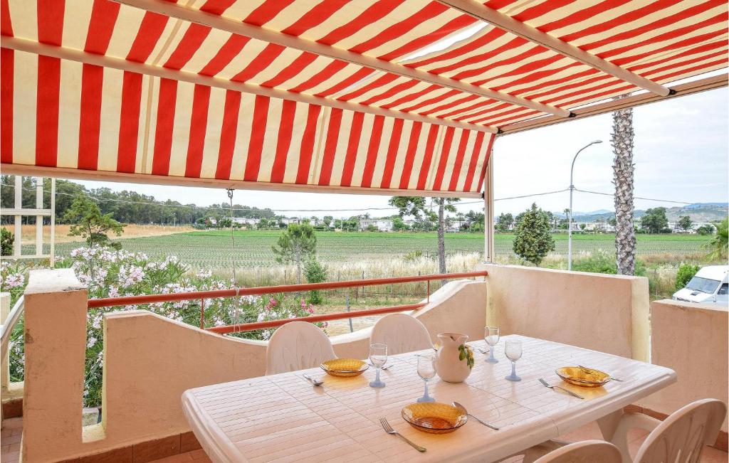 een witte tafel en stoelen onder een rode paraplu bij 1 Bedroom Awesome Apartment In Botricello in Botricello