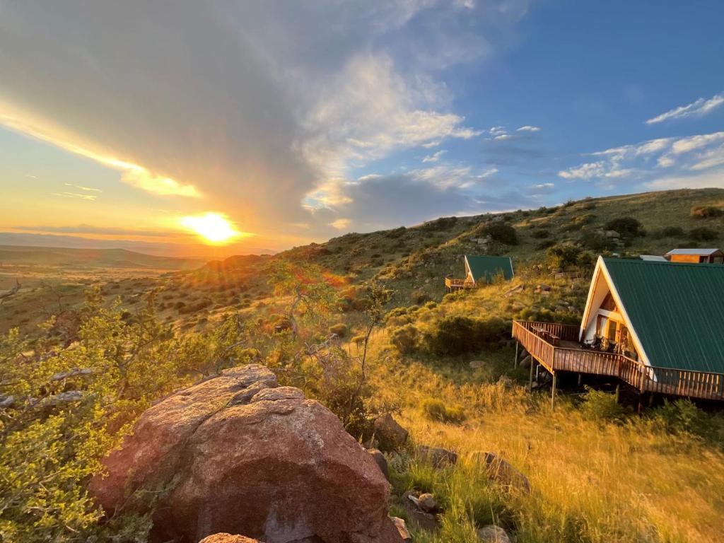 a cabin on a hill with the sunset in the background at Linduli Farmstay in Cradock