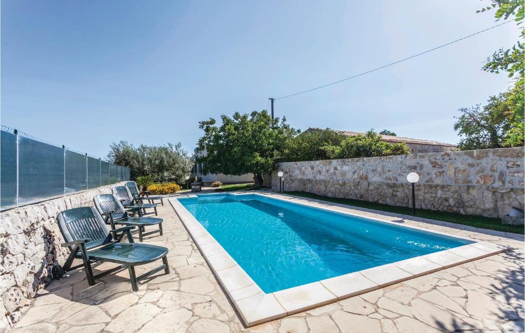 a swimming pool with chairs next to a stone wall at Casa Olivella in Cannizzara
