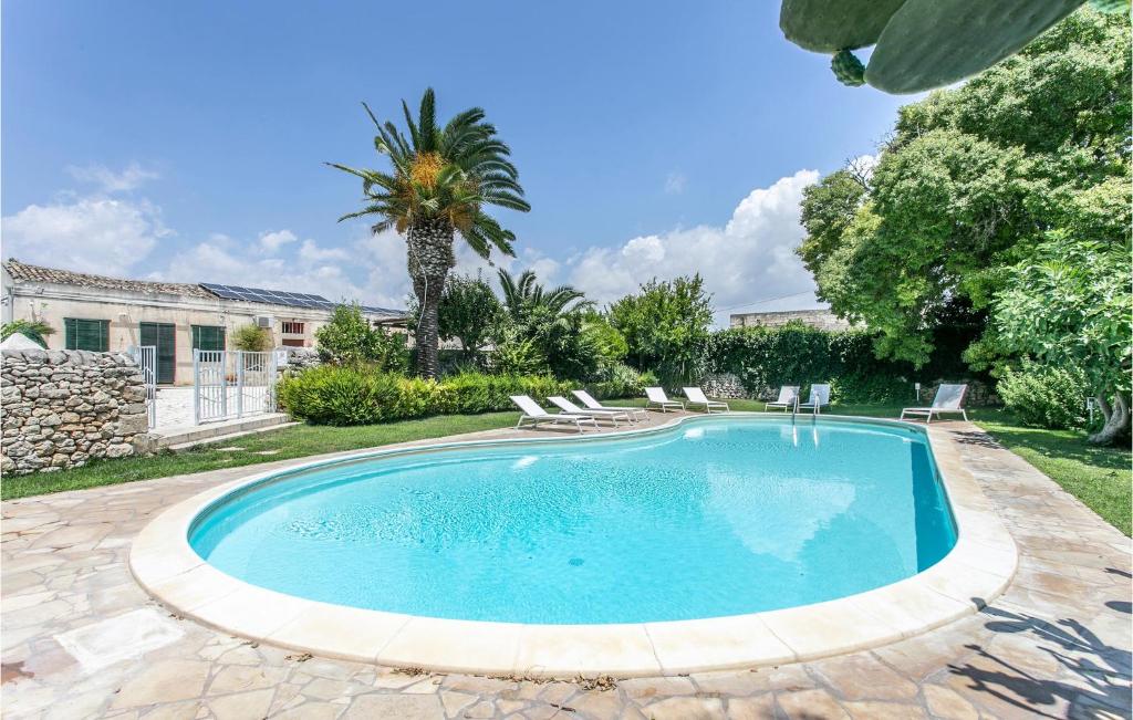 einen Pool in einem Garten mit Stühlen und einer Palme in der Unterkunft Casale Granati in Rosolini