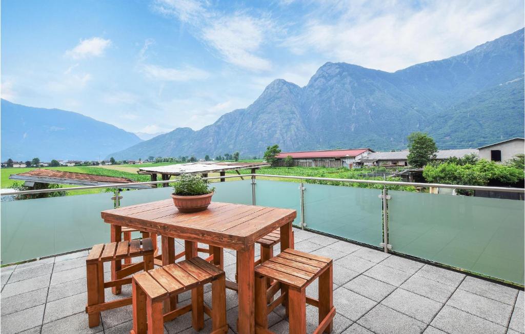 d'une table en bois et de deux chaises sur un balcon avec vue sur les montagnes. dans l'établissement Casa Meno, à Novate Mezzola