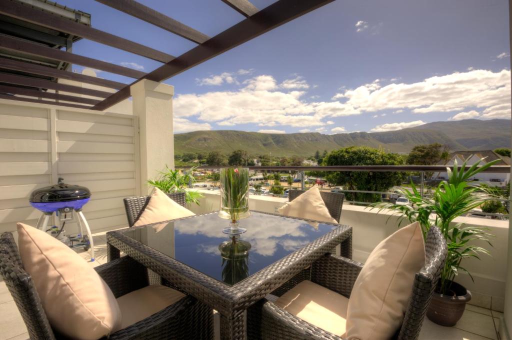 eine Terrasse mit einem Glastisch und Stühlen auf dem Balkon in der Unterkunft Whale Coast All-Suite-Hotel - DCC Hotel Group in Hermanus