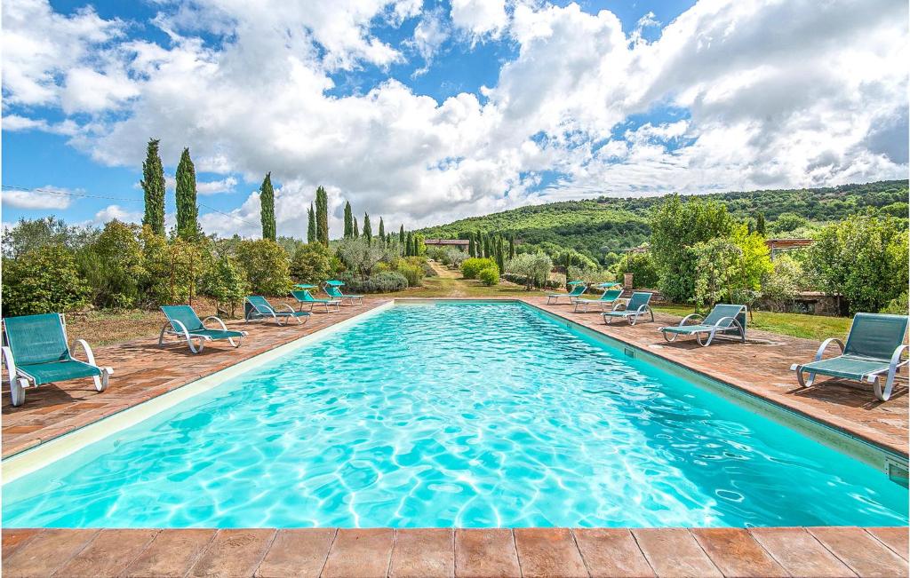 a swimming pool with blue chairs and trees and a sky at Villa San Venanzo in Baccano