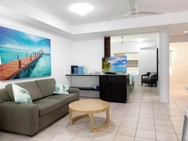 a living room with a couch and a tv and a table at REEF RETREAT APARTMENTS PALM COVE Unit 13 in Palm Cove