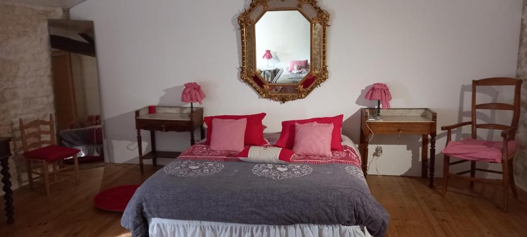 a bedroom with a bed with red pillows and a mirror at Gîte Rouge Calme et Nature in Allas-Bocage