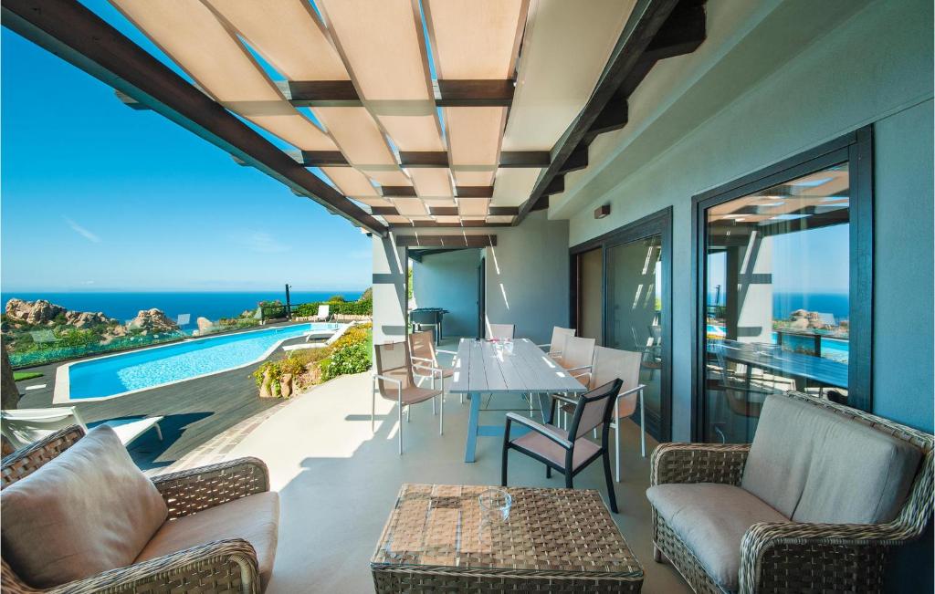 a patio with a table and chairs and a view of the ocean at Stunning Home In Trinitadagultu Ot With 6 Bedrooms, Wifi And Outdoor Swimming Pool in Costa Paradiso
