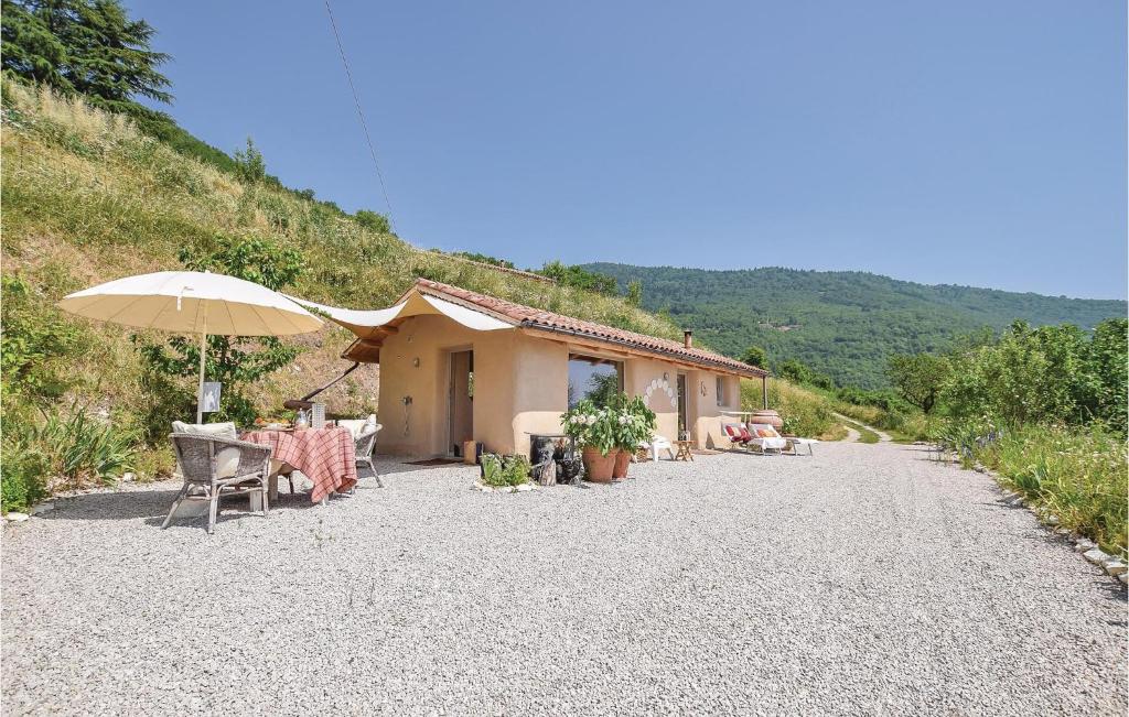 a house with a table and an umbrella on a gravel road at Chalet Calvenere in Calvene