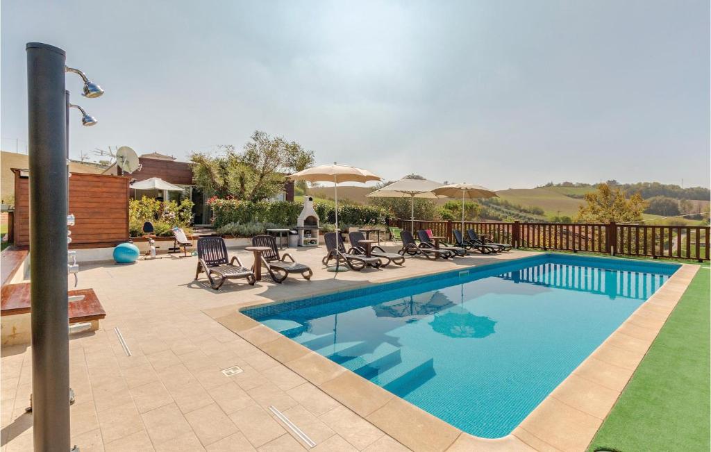 a swimming pool with chairs and umbrellas on a patio at Casa Federica in Monte San Giusto